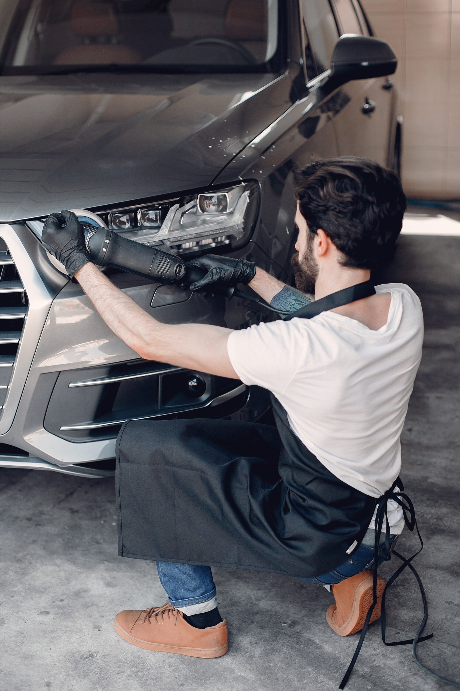 Man in a garage. Worker polish a car.