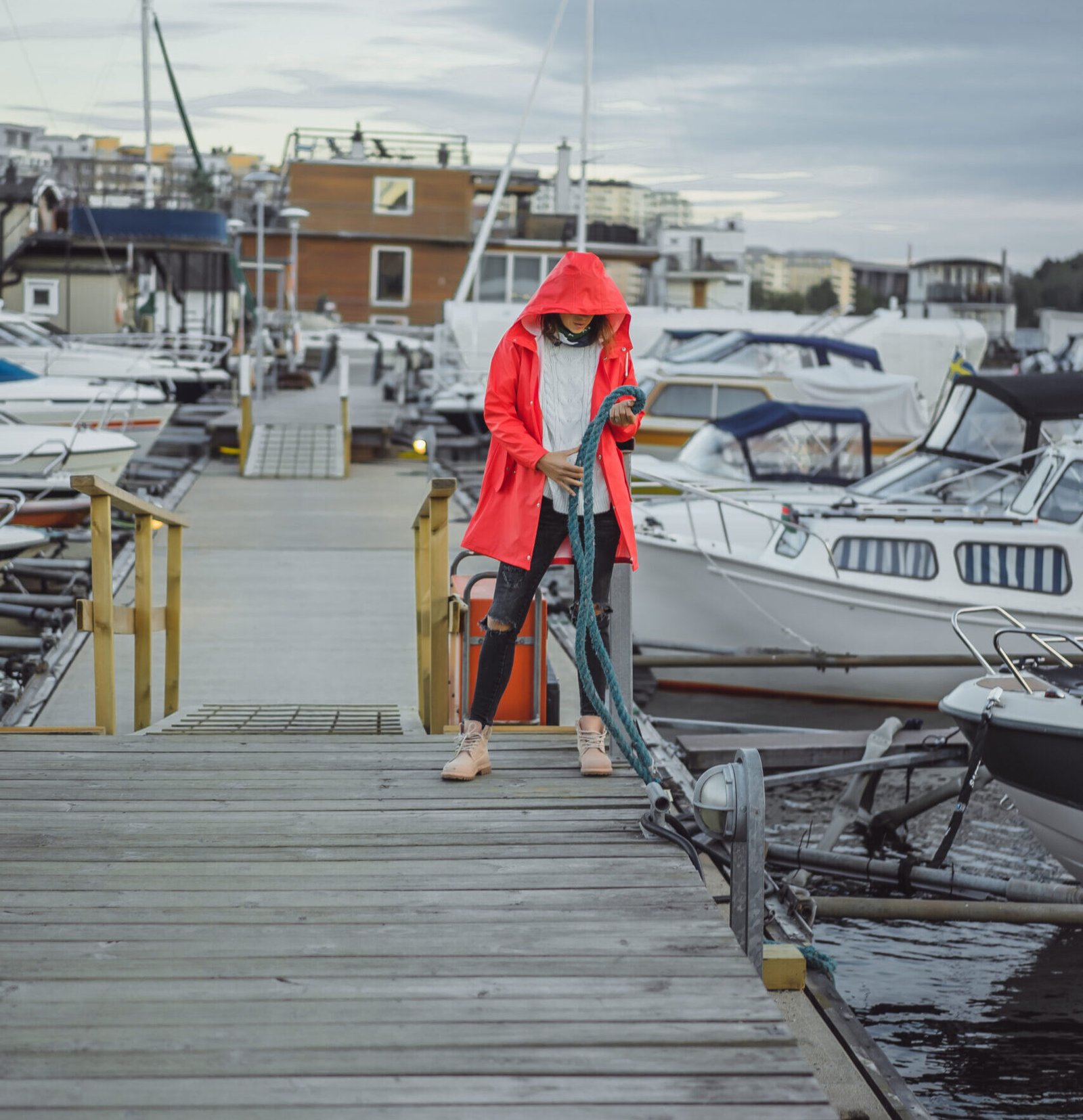 Beautiful young woman in a red cloak in the yacht port. Stockholm, Sweden